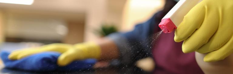 gloved hands using cleaning spray 