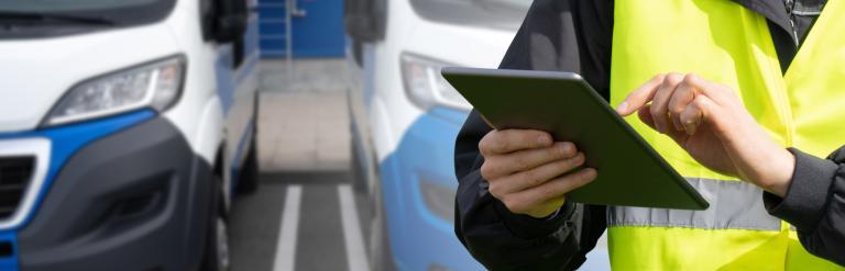 Person with tablet computer standing near a van