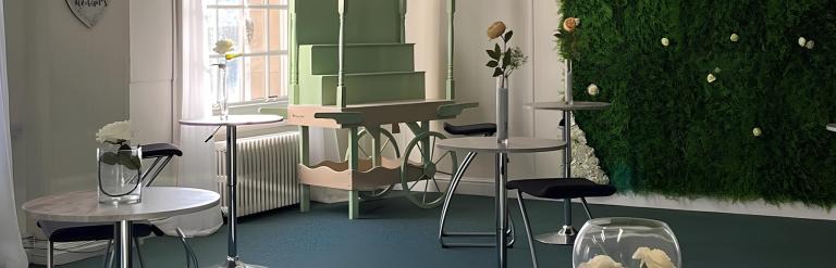 The inside of a room with small tables, several chairs, and fake grass on the wall
