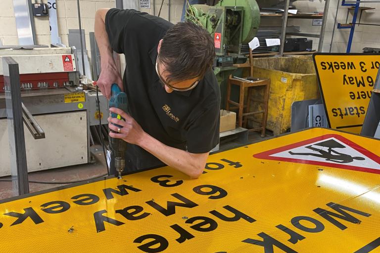 Person drilling into a large road sign